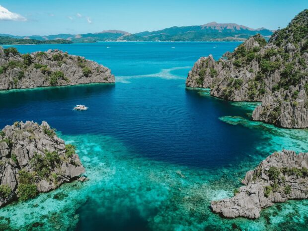 Beautiful Philippines crystal clear turquoise waters surrounded by rocky islands and lush greenery