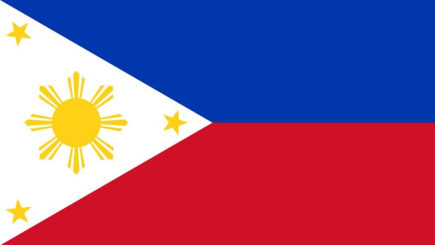 The Philippines flag with a white triangle and yellow sun and stars on blue and red stripes