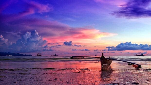 Traditional Philippines boat resting on the shore under a colorful sunset sky