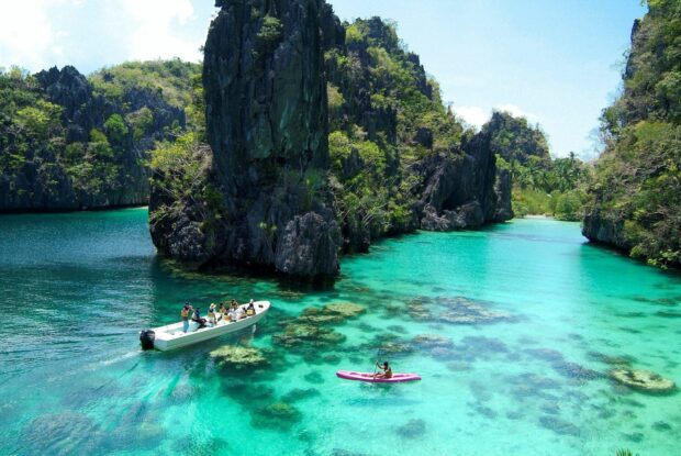 A scenic view of the Philippines with clear turquoise water and rocky islands surrounded by lush greenery