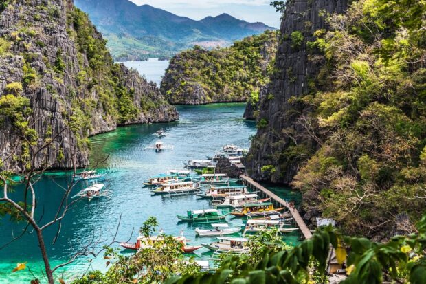 Traditional boats anchored in a scenic Philippines harbor surrounded by limestone cliffs and clear blue water