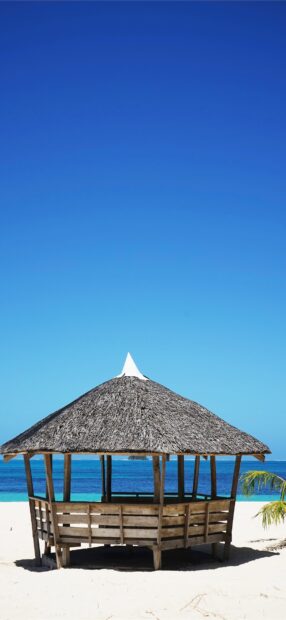 A traditional Philippines hut on the white sandy beach with clear blue sea and sky