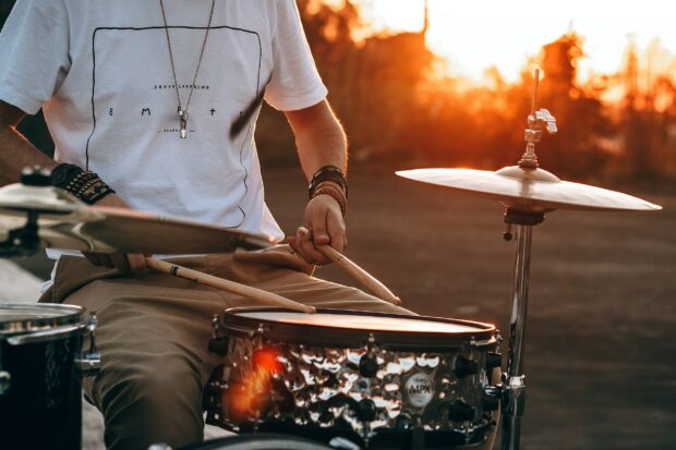 A person is playing drums with sticks during a warm sunset scene, 2K Desktop Wallpaper
