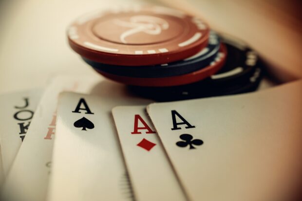 A poker hand with four aces and poker chips stacked on a table
