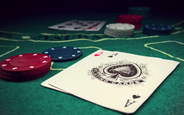 A close up of poker cards and chips on a green felt poker table