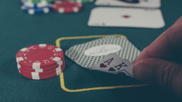 A poker hand of ace and king of hearts being revealed on the green felt table
