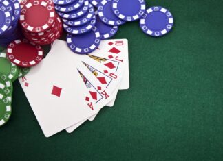 A poker hand with diamond cards and colorful poker chips on a green felt table