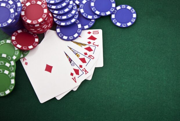 A poker hand with diamond cards and colorful poker chips on a green felt table