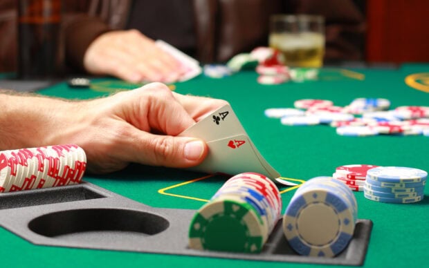 A poker player holding aces during a card game on a green felt poker table