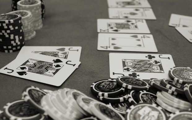A poker table with playing cards and stacks of poker chips in a black and white setting
