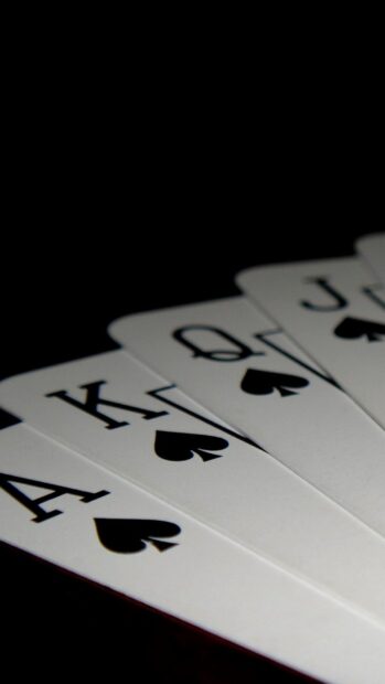 A royal flush with spades cards displayed in a fan shape on a black surface