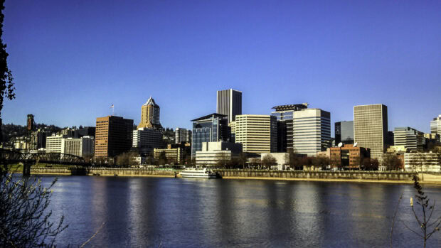 A clear view of Portland skyline with river in the foreground and blue sky above