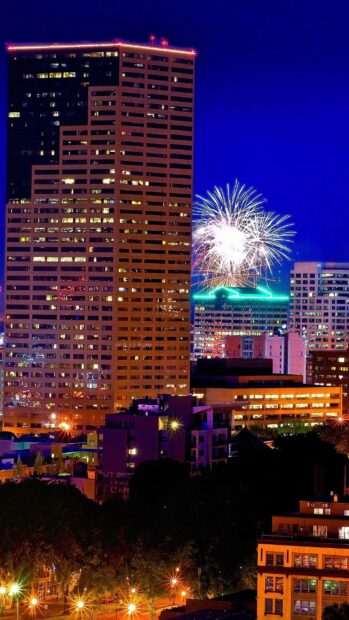 Fireworks illuminate the Portland skyline at night featuring tall buildings and a bright cityscape