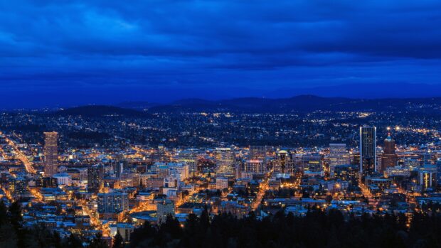A vibrant view of Portland skyline at night showing city lights and hills in the background