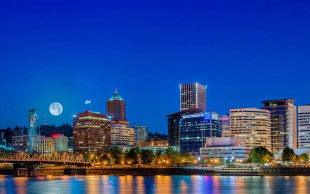Portland skyline with a full moon over the river at night in vibrant colors