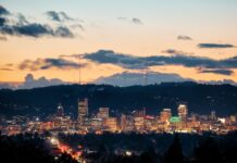 The Portland skyline at dusk with city lights and hills in the background
