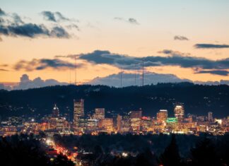 The Portland skyline at dusk with city lights and hills in the background