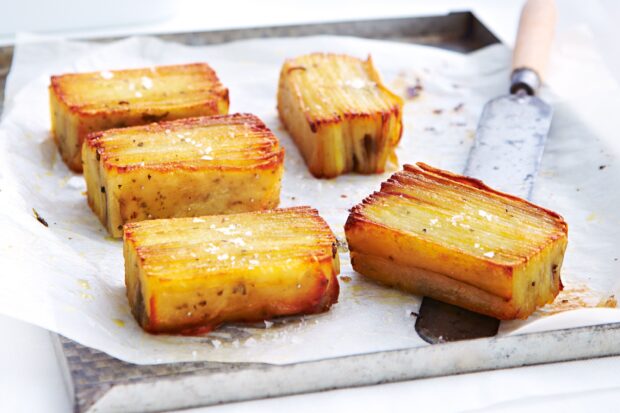 Golden roasted potato pieces sprinkled with sea salt on baking paper without background