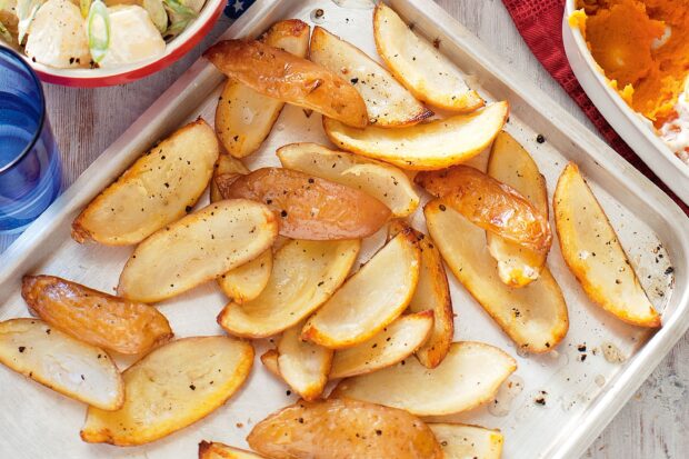 Roasted potato wedges seasoned with black pepper on a baking tray ready to eat
