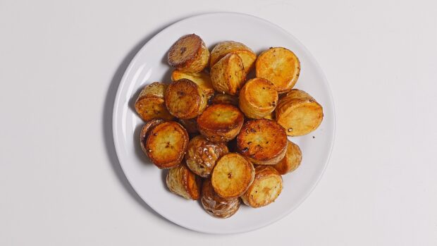 Roasted potato pieces served on a white plate with a clean background
