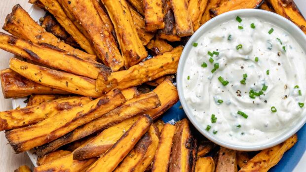 Roasted potato sticks served with creamy herb dip on a blue plate