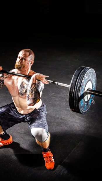 A muscular man performs a heavy weightlifting move in Crossfit training, 2K Phone Wallpaper