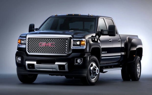 A black GMC truck is shown from the front with detailed grill and headlights, HD Desktop Wallpaper
