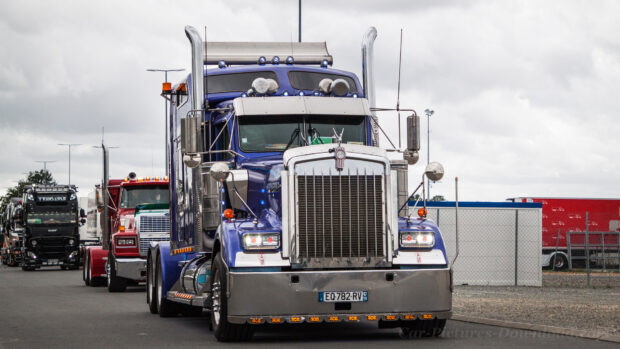 A blue Kenworth truck leads a line of trucks waiting on the road under a cloudy sky, HD Desktop Wallpaper