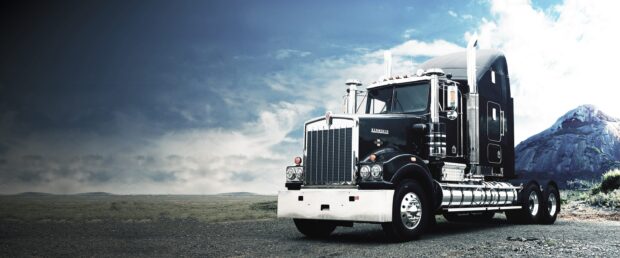 A Kenworth truck is parked on a deserted plain with a cloudy sky and mountain in the background, 2K Desktop Wallpaper