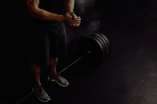 A man prepares for a powerlifting lift by chalking his hands, 2K Desktop Wallpaper