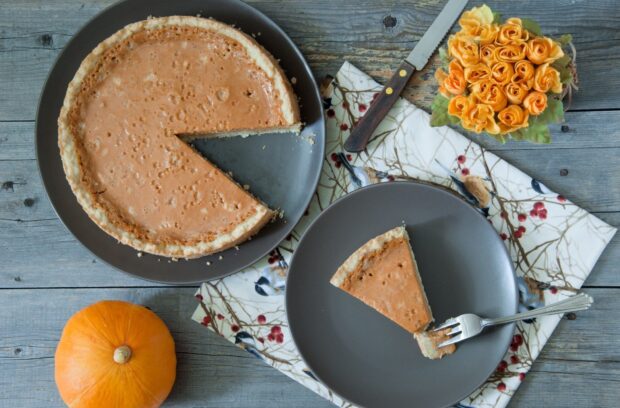 A pumpkin pie with a slice served on a gray plate next to a small pumpkin and flowers, HD Desktop Wallpaper