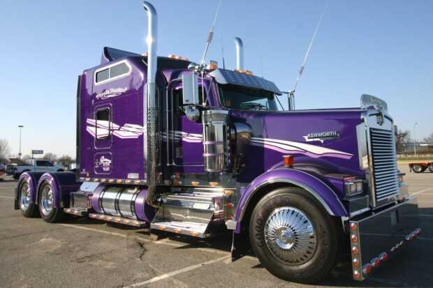 A purple Kenworth truck is parked under clear skies showing detailed chrome features, HD Desktop Wallpaper