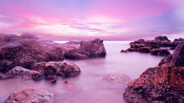 A serene scenery wallpapers with rocky shore and soft mist under a pink sky at sunset, 4K Desktop Wallpaper