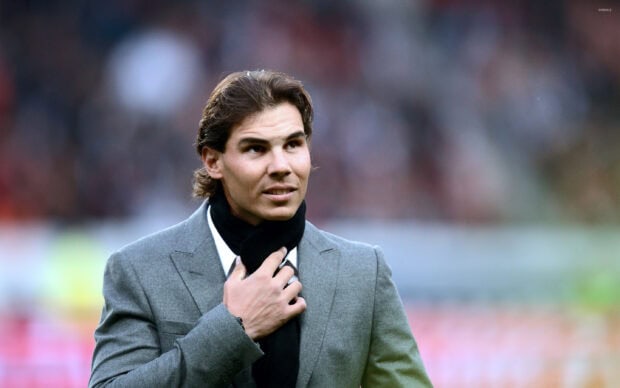 Rafael Nadal in a gray suit with a black scarf looking to the side in an outdoor setting, 2K Desktop Wallpaper