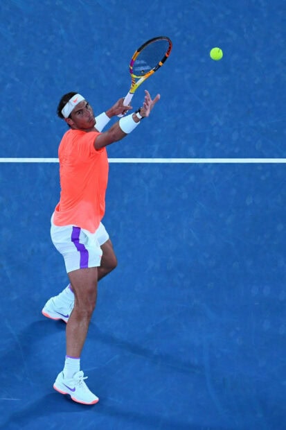 Rafael Nadal is focused on hitting a tennis ball during a match, HD Mobile Wallpaper
