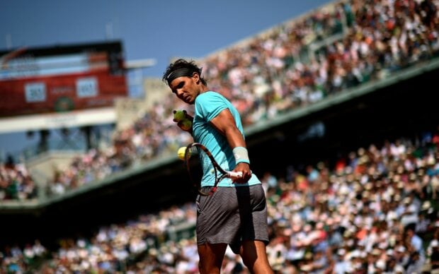 Rafael Nadal serving a tennis ball during a match with a crowd watching, 2K Desktop Wallpaper