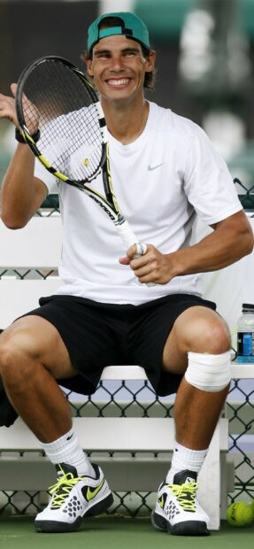 Rafael Nadal is sitting and smiling while holding a tennis racket during practice, 2K Mobile Wallpaper