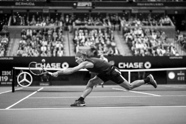 Rafael Nadal stretching to hit a tennis ball during a professional match with a crowd watching, 2K Desktop Wallpaper