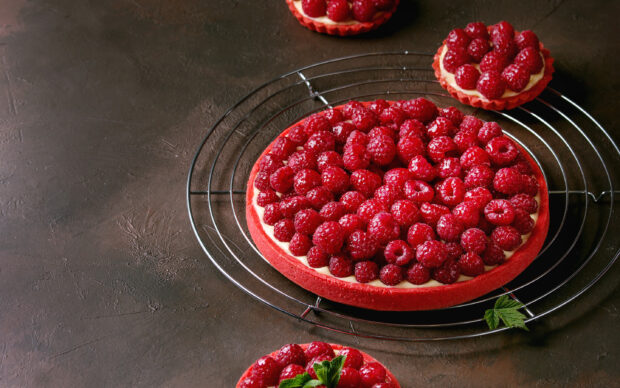 A raspberry pie topped with fresh raspberries resting on a cooling rack, 2K Desktop Wallpaper