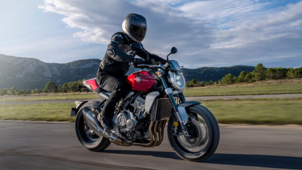 A rider is cruising on a red Honda CB1000R motorcycle near mountains, 4K Desktop Wallpaper