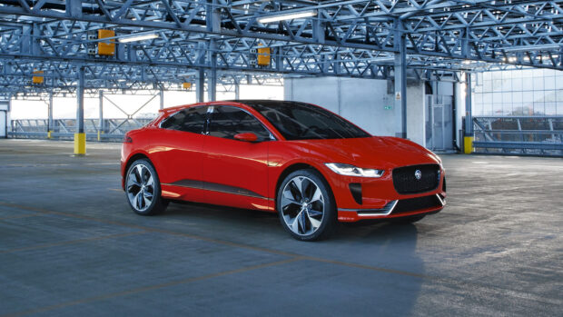 A red Jaguar I Pace is shown parked in an industrial garage with metal beams overhead, HD Desktop Wallpaper