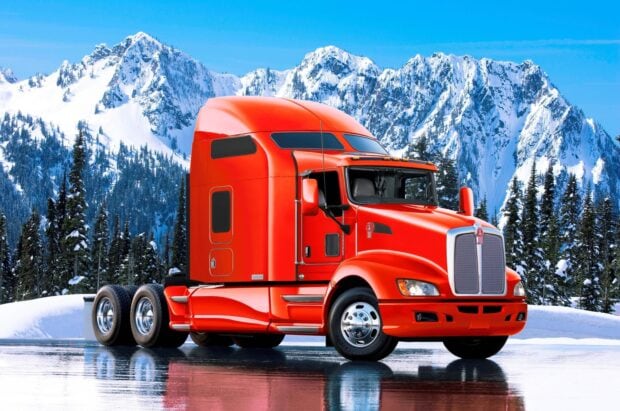 A red Kenworth truck is parked on a smooth icy surface with snow covered trees and mountains in the background, 2K Desktop Wallpaper