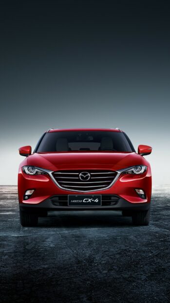 A red Mazda CX 4 is shown from the front on a dark textured surface under a clear sky, 2K Phone Wallpaper