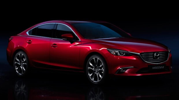 A red Mazda car shines brightly in a dark studio setting, showcasing its elegant design and smooth curves, 4K Desktop Wallpaper