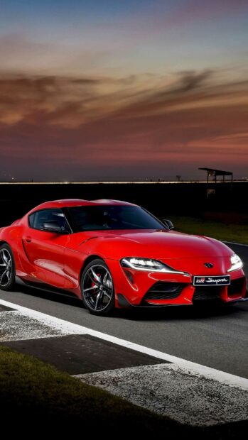 Red sports car, Toyota GR Supra, 2023, sleek modern vehicle, sunset background.