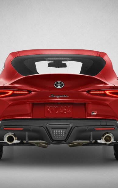 Red Toyota Supra GR sports car with sleek rear design and dual exhaust pipes.