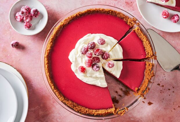 A red berry pie topped with whipped cream and fresh cranberries on a pink table, 2K Desktop Wallpaper