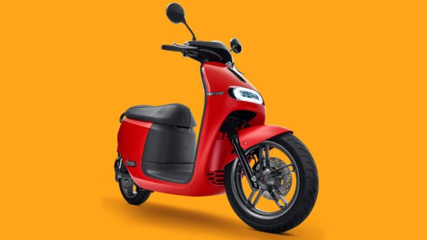A red scooter stands against an orange background showing its modern design and features, HD Desktop Wallpaper