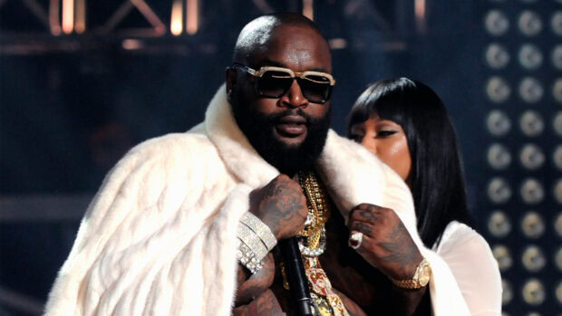 Rick Ross is wearing a fur coat and sunglasses while holding a microphone on stage, HD Desktop Wallpaper