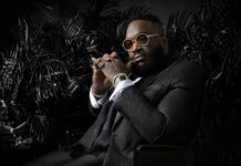 A confident man wearing a textured suit and gold sunglasses sitting thoughtfully, HD Desktop Wallpaper